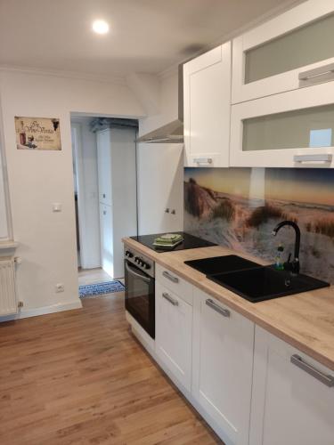 a kitchen with white cabinets and a sink at Ferienhaus kleine Perle in Stendal