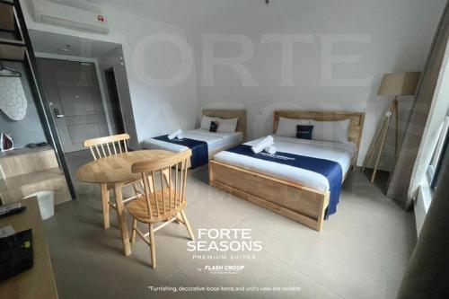 two beds in a room with a table and a chair at Forte Seasons Mossaz Premium Suites Petaling Jaya in Petaling Jaya