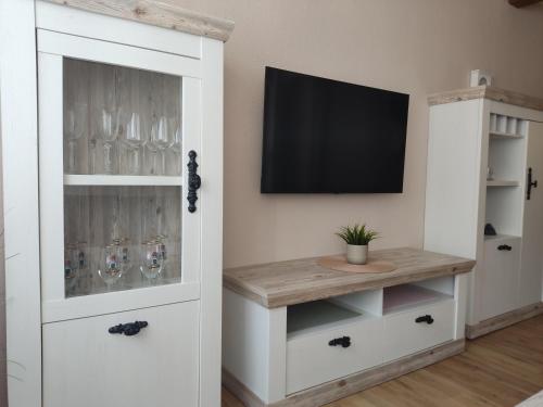 a room with a tv and a white cabinet with wine glasses at Ferienhaus kleine Perle in Stendal