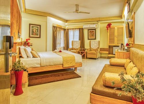a bedroom with a bed and a living room at Parklane Hotel in Mysore