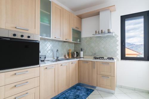 a kitchen with wooden cabinets and a large window at Casa Cuccureddu in Jerzu