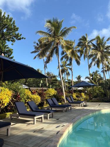 a row of chairs and umbrellas next to a swimming pool at Blue Lagoon Beach Resort in Nacula Island