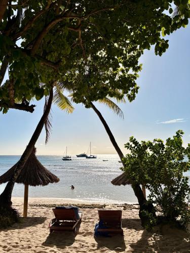 a beach with two chairs and a boat in the water at Blue Lagoon Beach Resort in Nacula Island