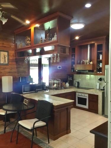 a kitchen with wooden cabinets and a table and chairs at Baan Laem Noi Villa's in Mae Nam