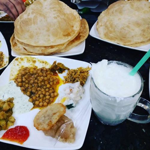 a table with plates of breakfast food and a drink at Hilton Family Guest House in Lahore