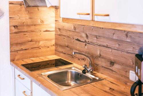 a kitchen with a sink and a wooden wall at Landhaus Perktold in Nesselwängle