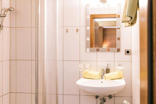 a white bathroom with a sink and a mirror at Landhaus Perktold in Nesselwängle