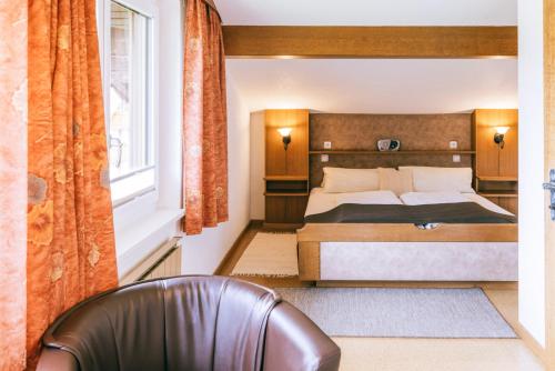 a bedroom with a bed and a chair and a window at Landhaus Perktold in Nesselwängle