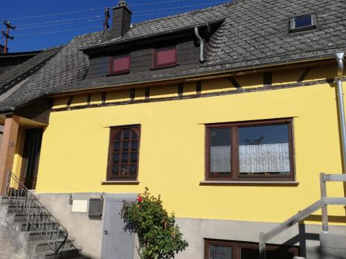 a yellow house with a black roof at Ferienhaus Koppenstein in Schwarzerden