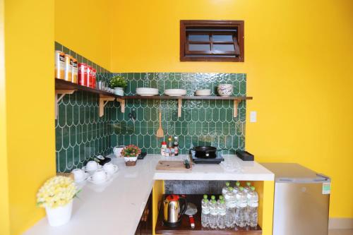 a small kitchen with yellow walls and green tiles at Hue Imperial Hostel in Hue