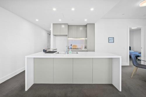 a white kitchen with a white island in a room at Fabulous view apartment in Sydney Olympic Park in Sydney