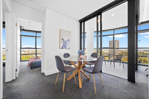 a dining room with a table and chairs and large windows at Fabulous view apartment in Sydney Olympic Park in Sydney
