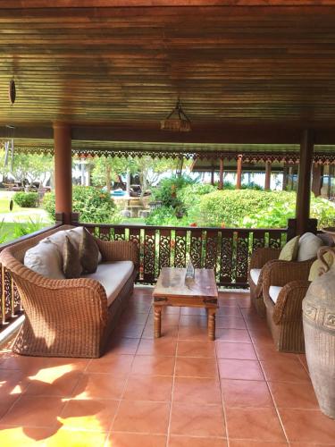 a living room with a couch and a table on a porch at Baan Laem Noi Villa's in Mae Nam