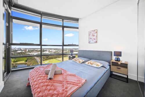 a bedroom with a bed and a large window at Fabulous view apartment in Sydney Olympic Park in Sydney