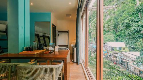 ein Esszimmer mit einem Tisch und einem großen Fenster in der Unterkunft J Boutique Hotel El Nido Managed by H Hospitality Group in El Nido