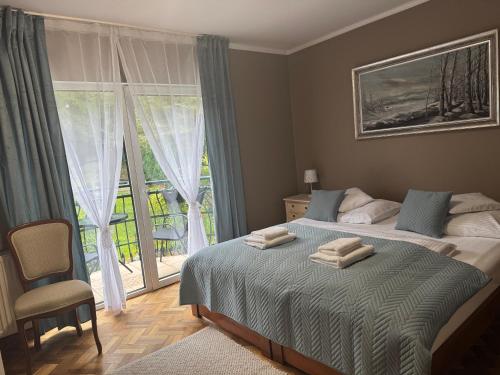 Un dormitorio con una cama y una ventana grande. en Jaśminowy Dwór Pensjonat, en Polanica-Zdrój