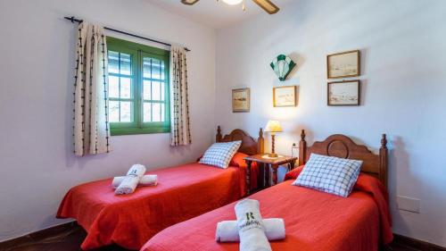 two twin beds in a room with red sheets at Casa El Torin Frigiliana by Ruralidays in Frigiliana