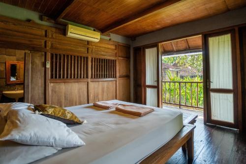 a large bed in a room with a window at Tembi - Historical Home in Yogyakarta