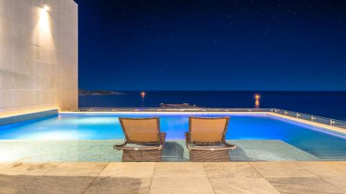 two chairs sitting next to a swimming pool at night at Goseong Moneblue Pension in Goseong