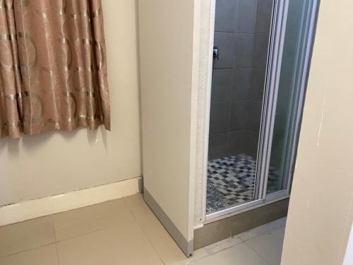 a shower with a glass door in a bathroom at JH Guest house in Durban