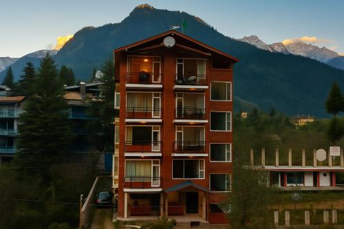 a tall building with a clock on top of it at Apple Flower Himalayan Heights - Luxury Stay with Mountain Views, Parking & Garden in Manāli