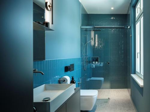 a blue bathroom with a sink and a toilet at Boutique Guesthouse - Marina Monfalcone in Monfalcone