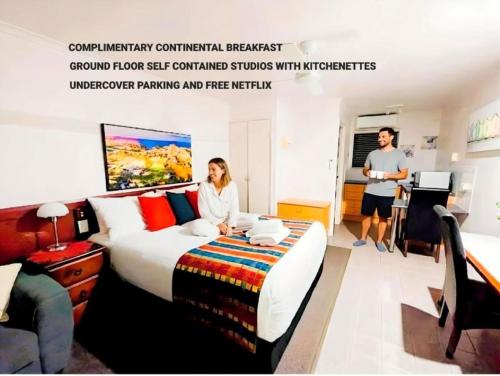 a woman sitting on a bed in a hotel room at Central Studio Accommodation in Gladstone