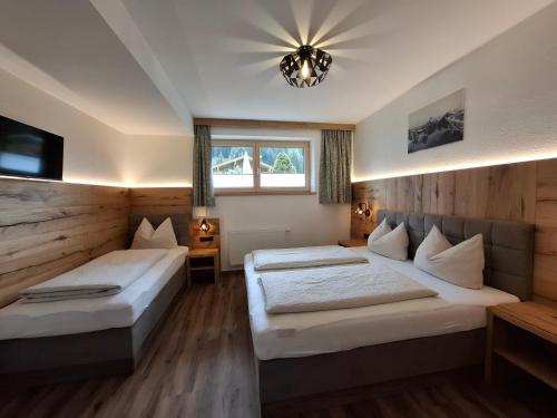 a bedroom with two beds and a chandelier at Ferienwohnungen Kirchler in Vorderlanersbach