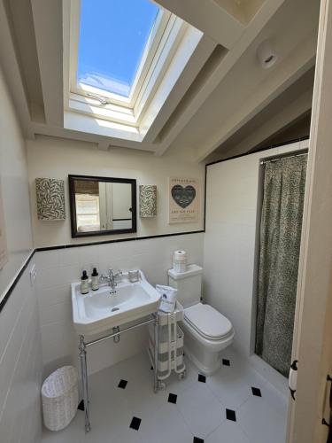 a bathroom with a sink and a toilet and a skylight at La Casita - Casa encantadora en Carriazo, Ribamontan al Mar, Cantabria in Carriazo