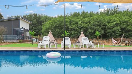 a group of chairs and tables next to a swimming pool at Anmyeondo Town 1967 Dog Pool Villa in Taean