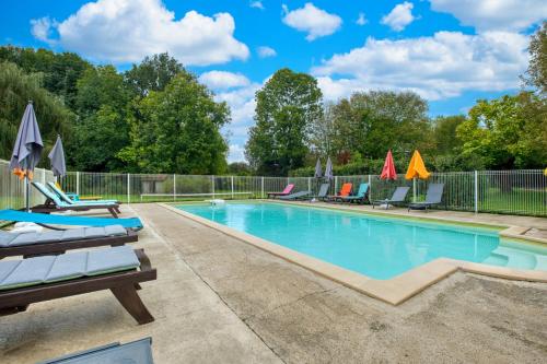 a swimming pool with lounge chairs and umbrellas at Gite Le Pont in Varaignes