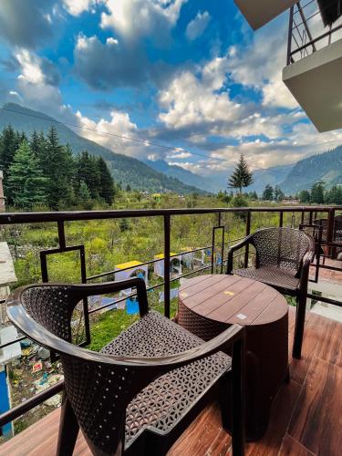 a table and two chairs on a balcony with a view at Apple Flower Himalayan Heights - Luxury Stay with Mountain Views, Parking & Garden in Manāli