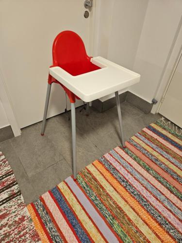 a red chair sitting next to a white desk on a rug at Apartment Enebacken close Göteborg in Mölnlycke