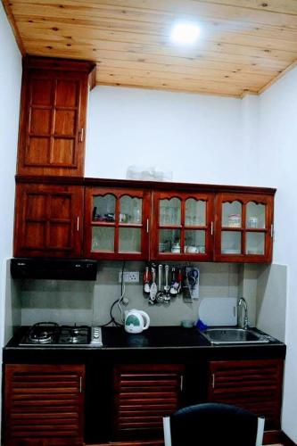 a kitchen with wooden cabinets and a black counter top at Elkaduwa Bungalow in Elkaduwa