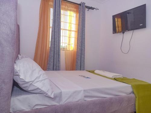 a bedroom with a bed with a tv and a window at Escape Hole in Diani Beach