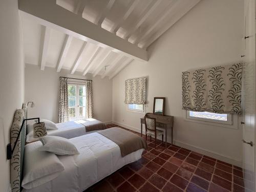 Un dormitorio con dos camas y una mesa y dos ventanas. en Los Sauces - Villa en Carriazo, Ribamontan al Mar, Cantabria, en Carriazo