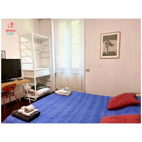 a bedroom with a blue bed and a television at Brixia Time Case - In villa con giardino in Brescia