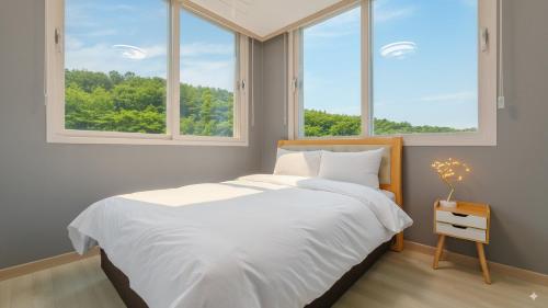 a bedroom with a bed and two windows at Taean Blueisland Pool villa in Taean