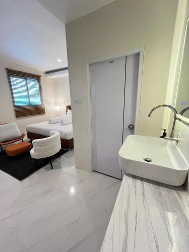 a white bathroom with a sink and a bed at Coconut Hill Koh Chang in Khlaung Phai Bae