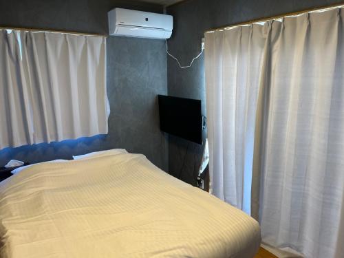 a bedroom with a bed and a tv and curtains at BOTH ISUMI - Vacation STAY 06928v in Isumi