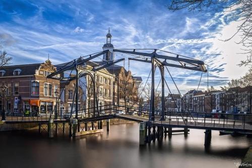 a bridge over a river in a city with buildings at Historic Canal-Side Apartment in Schiedam