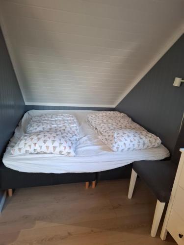 a bed with white sheets and pillows in a room at Charming studio apartment in Skarvedalen
