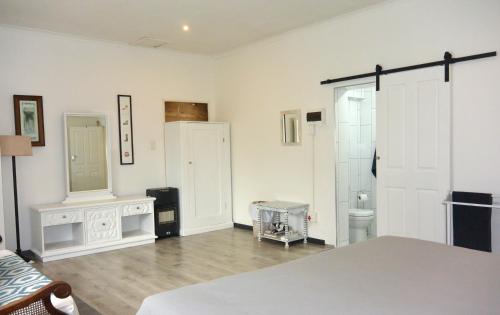 a white room with a bed and a mirror at Nirvana Cottage in Cape Town