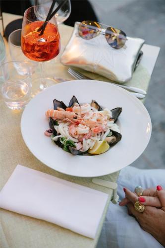 a plate of seafood on a table with a drink at Best Western Regina Elena in Santa Margherita Ligure