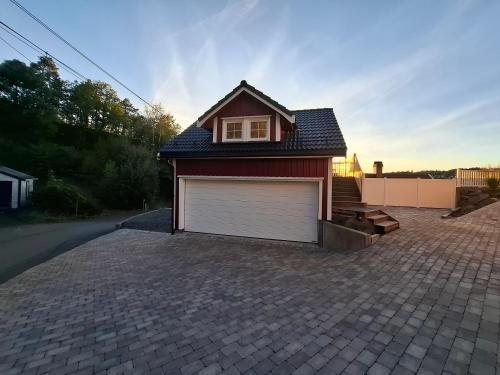 a house with a garage on a driveway at Charming studio apartment in Skarvedalen