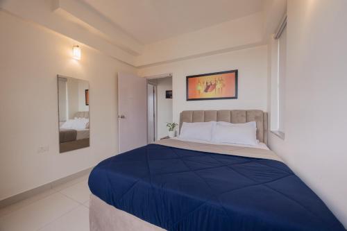 a bedroom with a large bed with a blue blanket at Velora Vista by JadeCapsMultiSpeciality Hospital in Thakurpukur