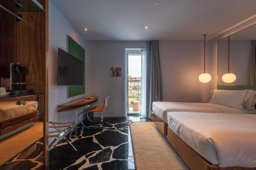 a hotel room with two beds and a desk at Hotel Calimala Milano in Milan