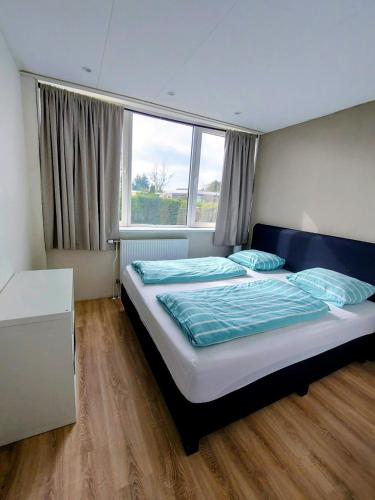 a bedroom with a bed and a large window at Plattedijk - vakantiehuis 25-26 in Lemmer