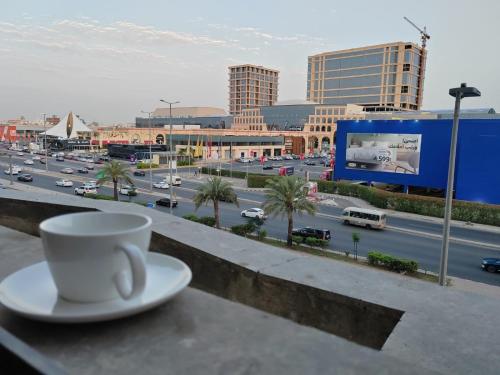 a cup of coffee sitting on a ledge with a city at استوديو السعودية - التحلية 411 Saudi Studio -Tahlia in Jeddah