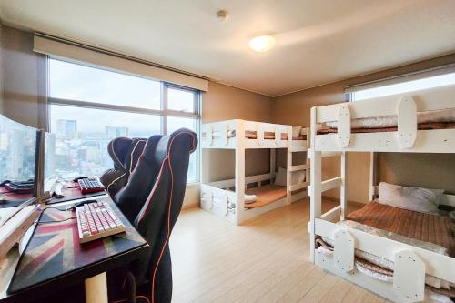 a room with bunk beds and a desk with a computer at Joy Hotel in Jeju